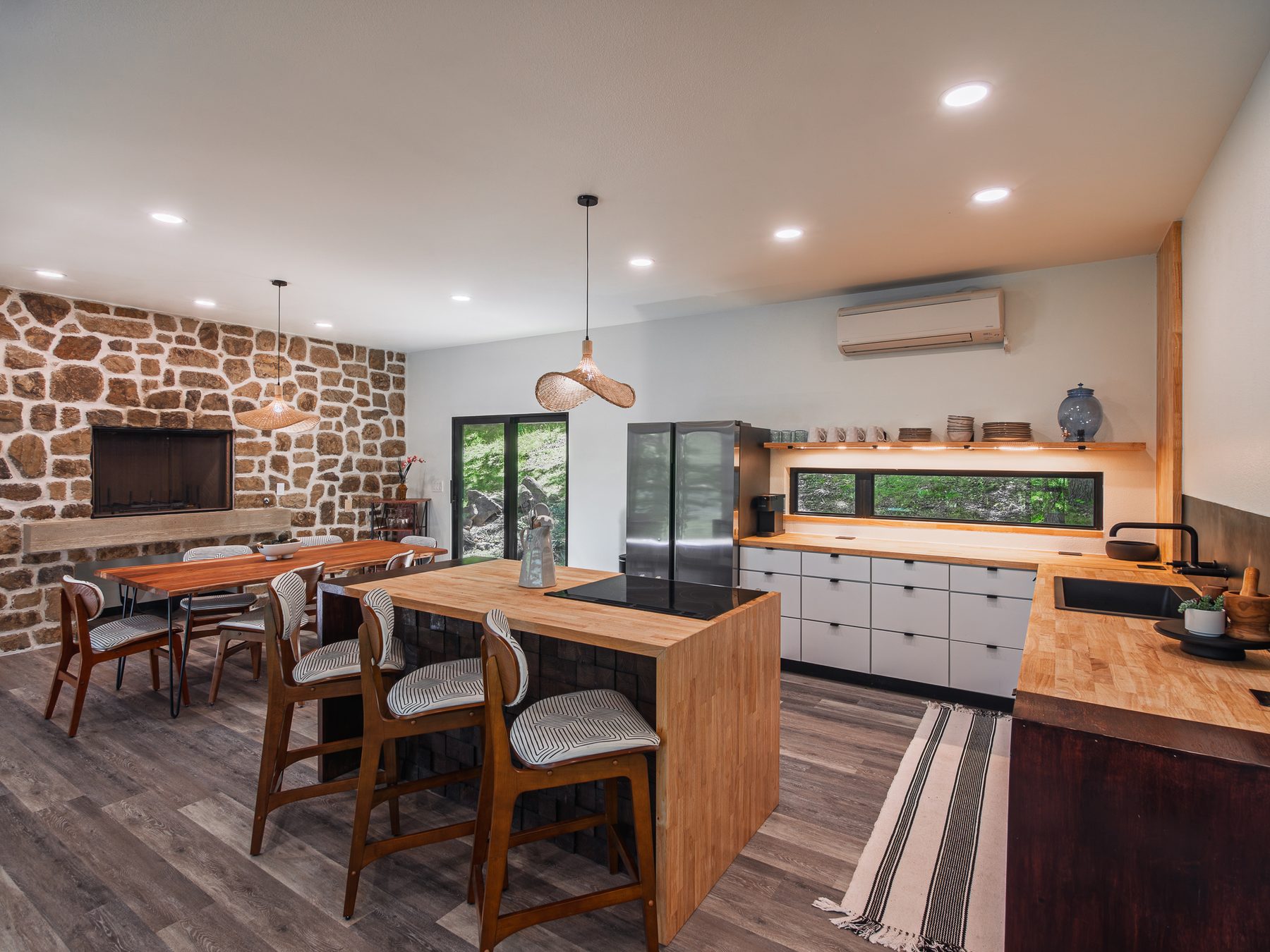 Arrow Lane kitchen and dining area with a native stone fireplace wall, butcher-block island and woven pendant lights